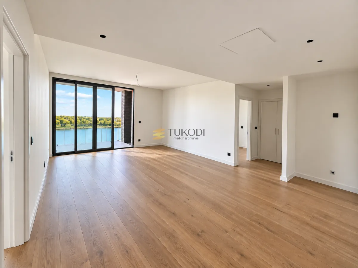 Empty room with wooden flooring and large glass doors leading to a balcony.