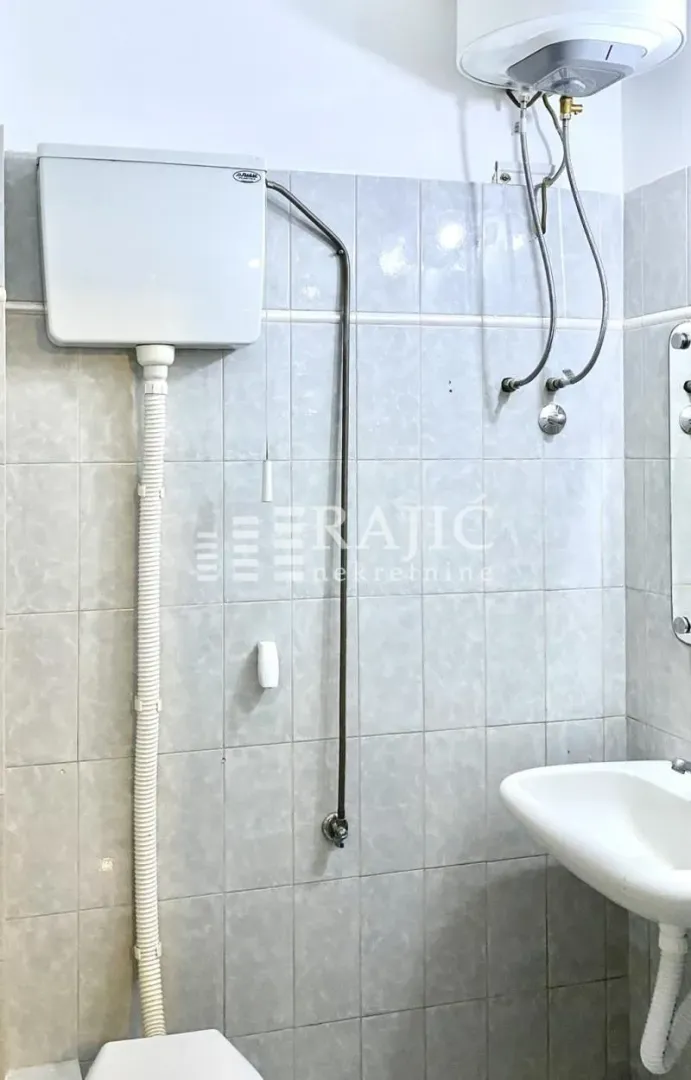 Small bathroom with tiles, a sink, and a water heater.