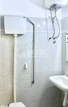 Small bathroom with tiles, a sink, and a water heater. - image 17