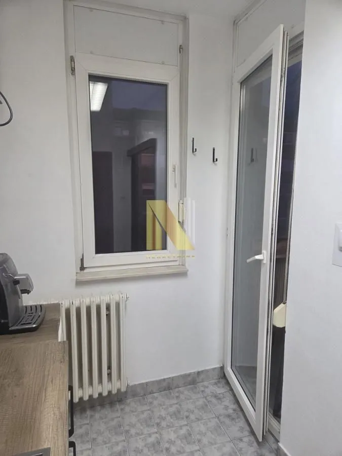 Manja kuhinja sa belom stolarijom i keramičkim pločicama na podu.