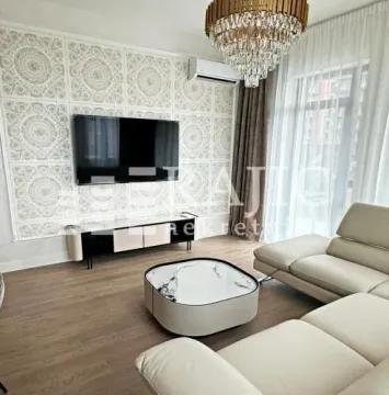 Living room with a sofa, TV, and decorative chandelier. - image 3