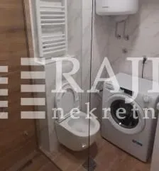 Smaller bathroom with a toilet, washing machine, and walk-in shower. - image 4