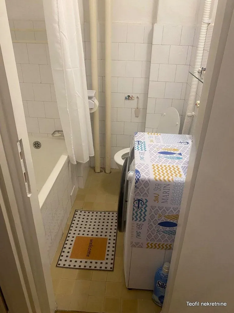 Manje kupatilo sa kadom, toaletom i veš mašinom.