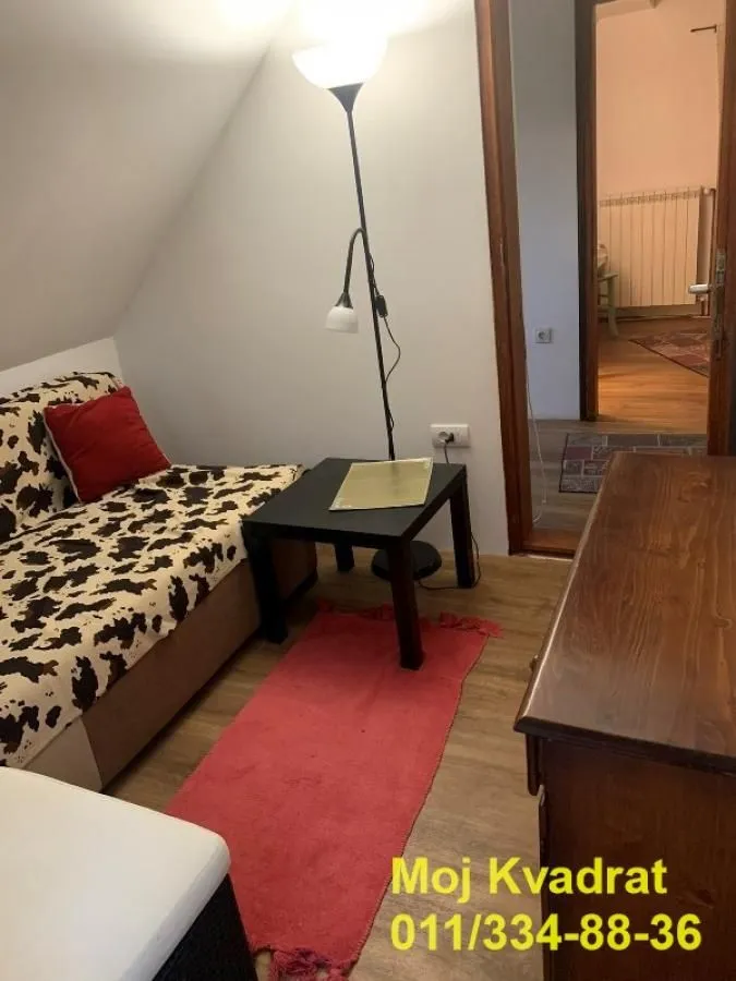 Manja soba sa krevetom, stočićem i podnom lampom.