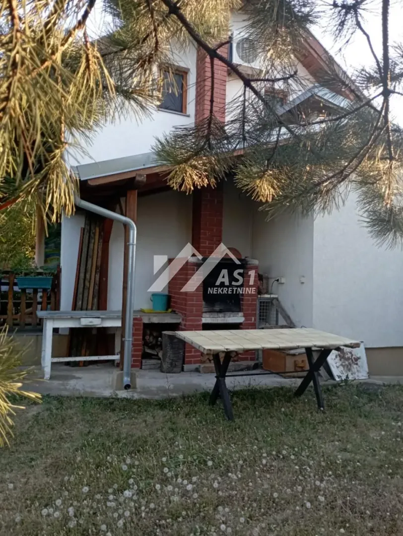 Dvorište kuće sa zidanim roštiljem i stolom za sedenje.