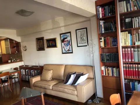 Bright living room featuring a leather sofa, a large bookcase, and a dining area. - image 5