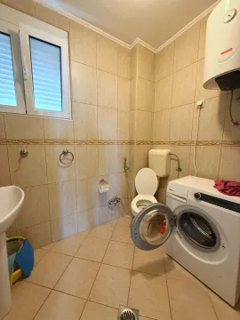 Kupatilo obloženo keramičkim pločicama sa toaletom, umivaonikom i veš mašinom. - image 6