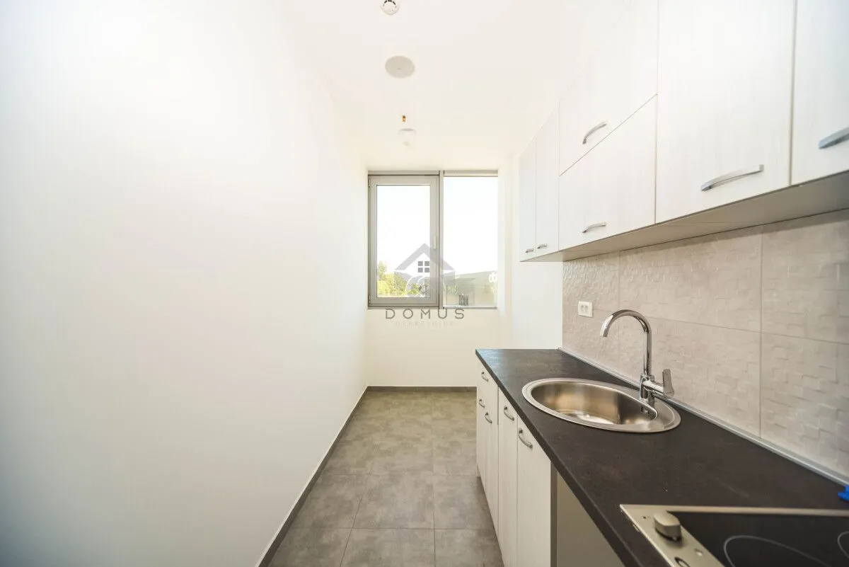 Small bright kitchen with white units and dark countertops.