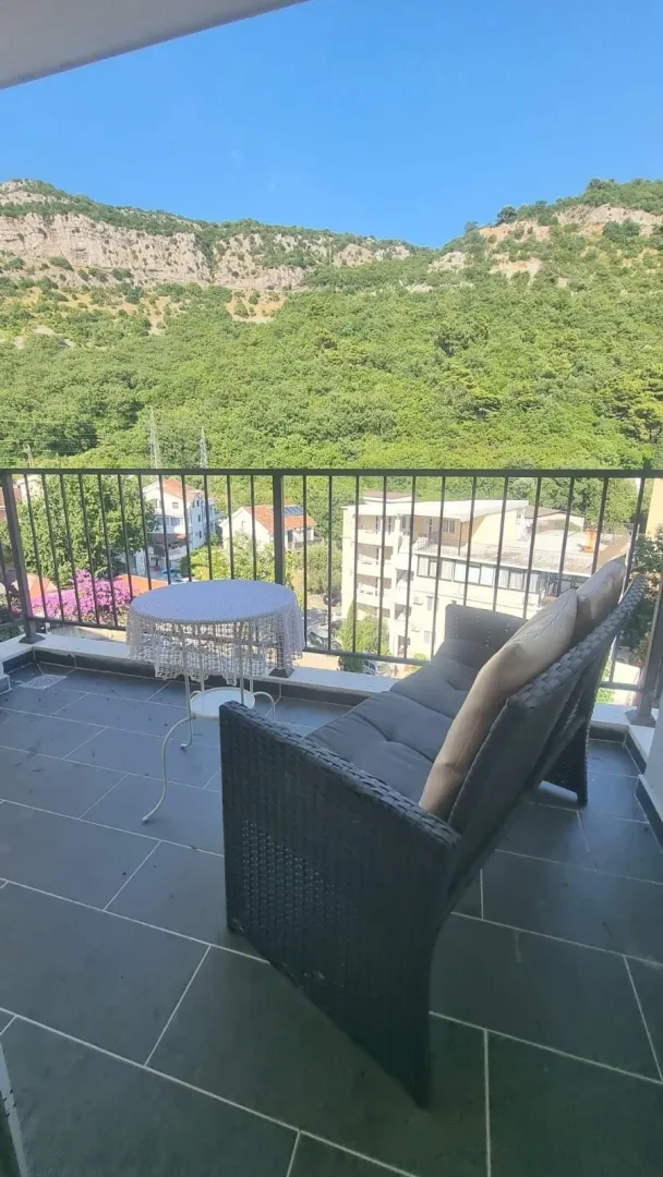 Furnished terrace with seating furniture and a view of nature and surrounding buildings.