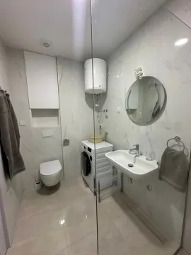 Svijetlo kupatilo sa veš mašinom i okruglim ogledalom. - image 3