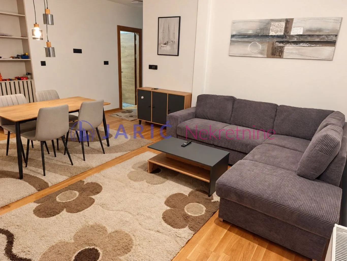 Living room with a sofa, dining table, and rugs.