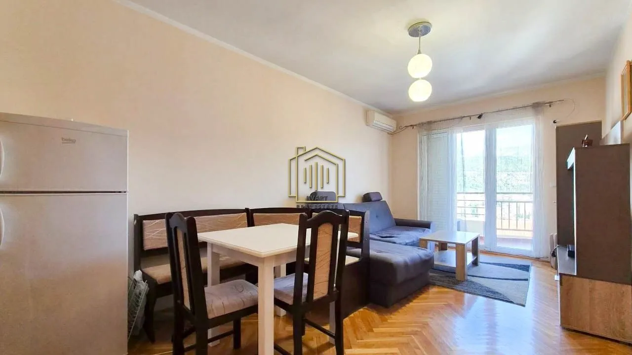 Dnevni boravak sa garniturom, trpezarijskim stolom i kuhinjskim dijelom.