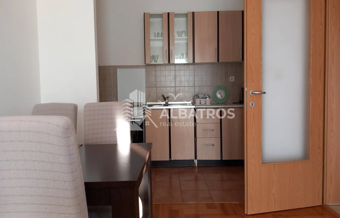 Smaller kitchen with wooden cabinets and a dining table in the foreground.