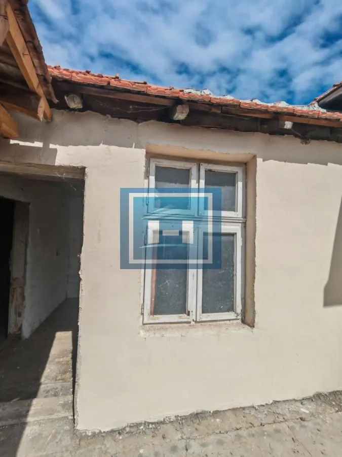 Pogled na spoljni deo starije kuće sa prozorom i krovnom konstrukcijom.