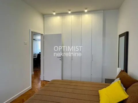 Furnished bedroom with a double bed, large built-in wardrobe, and a mirror. - image 13