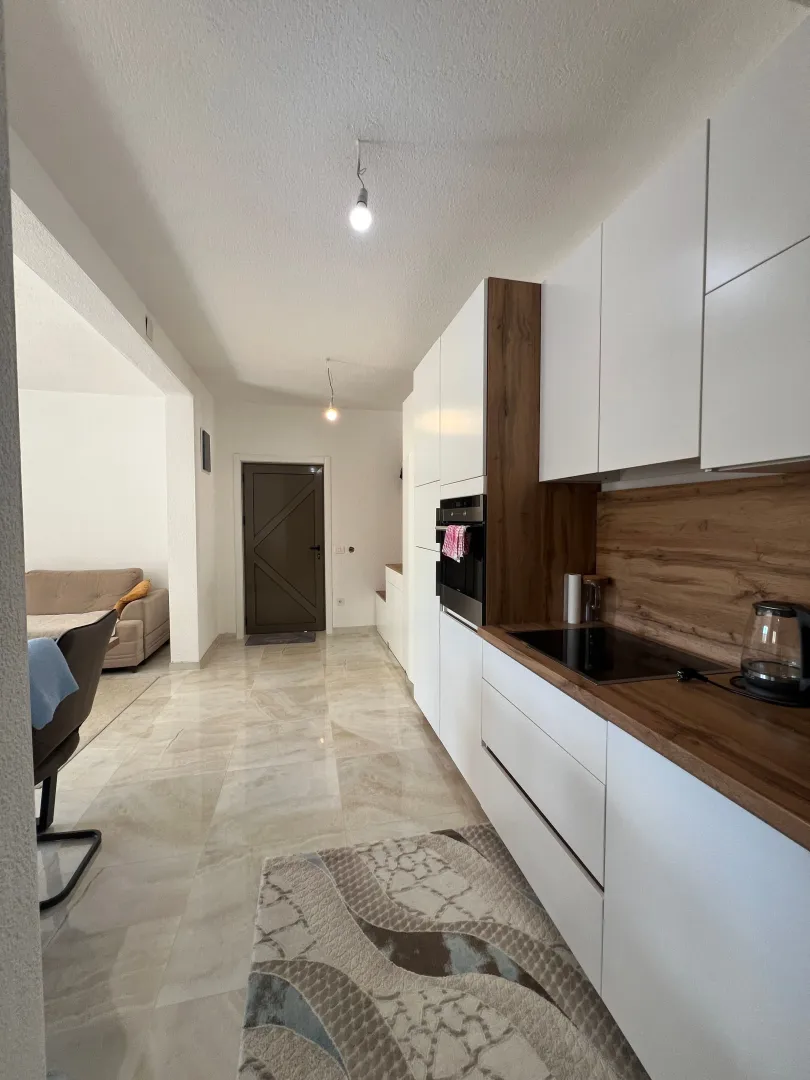 Modern kitchen with white cabinets and wooden countertops in an open space layout.