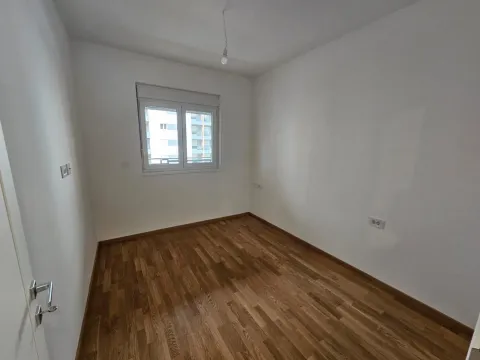 Prazna soba sa bijelim zidovima, drvenim podom i jednim prozorom. - image 5