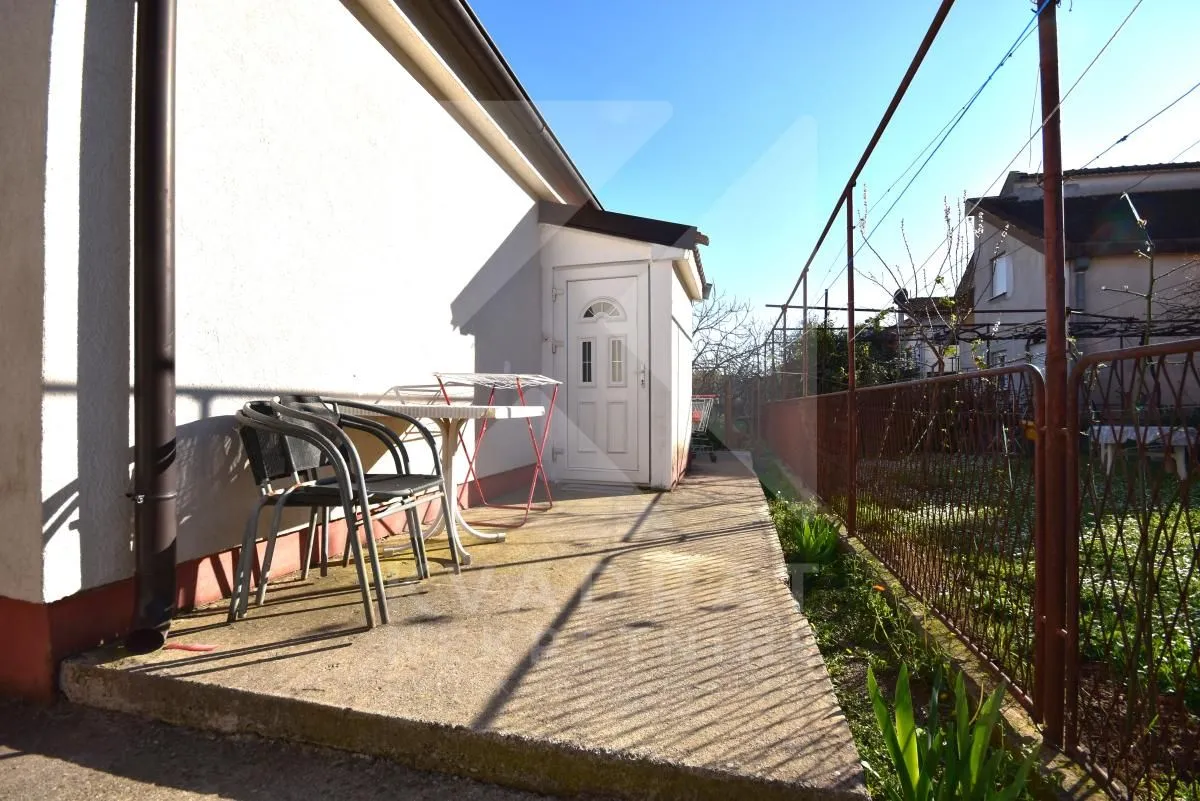 Paved courtyard area next to the house with a table and chairs.
