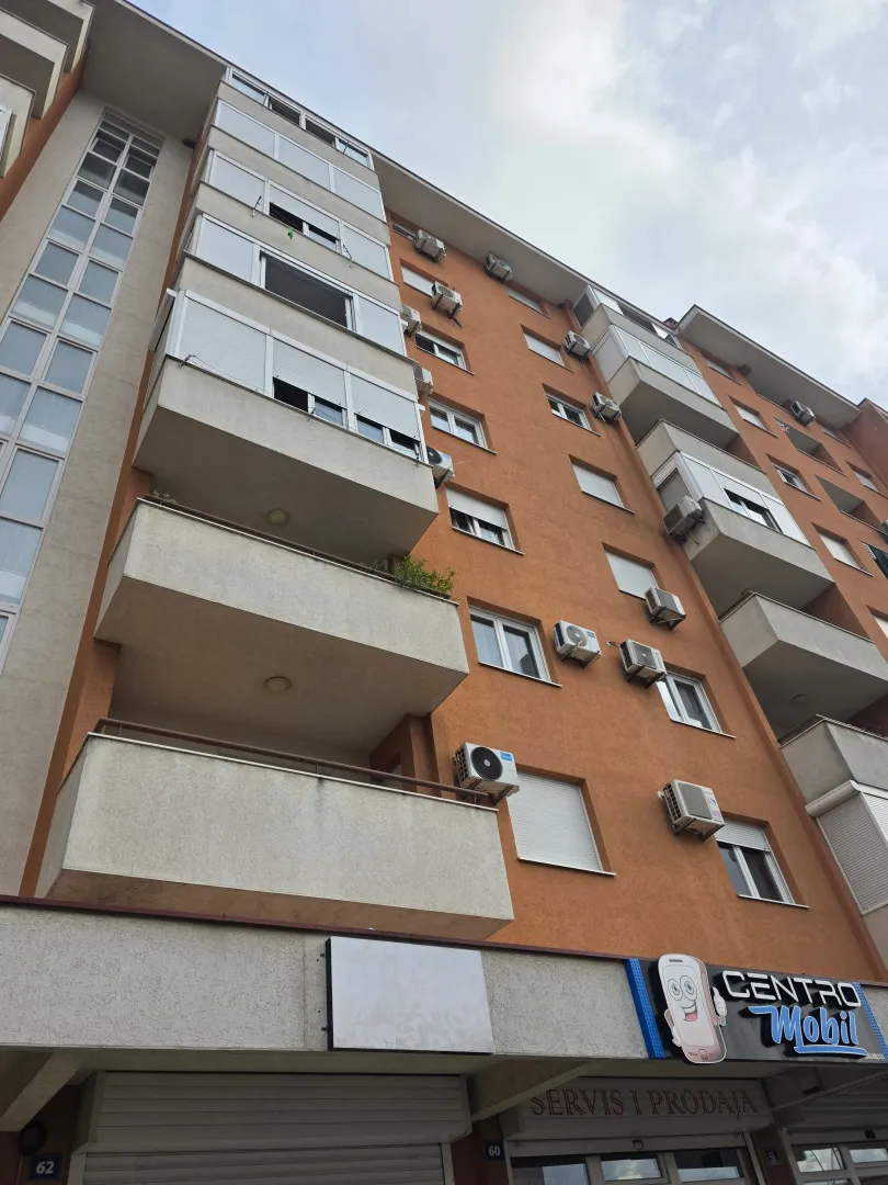 Spoljašnji izgled stambene zgrade sa balkonom i poslovnim prostorom u prizemlju.