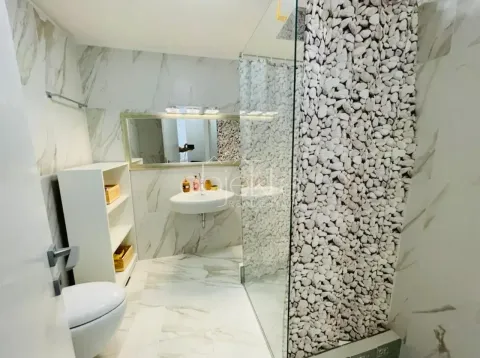 Modern bathroom with marble tiles and a walk-in shower. - image 7