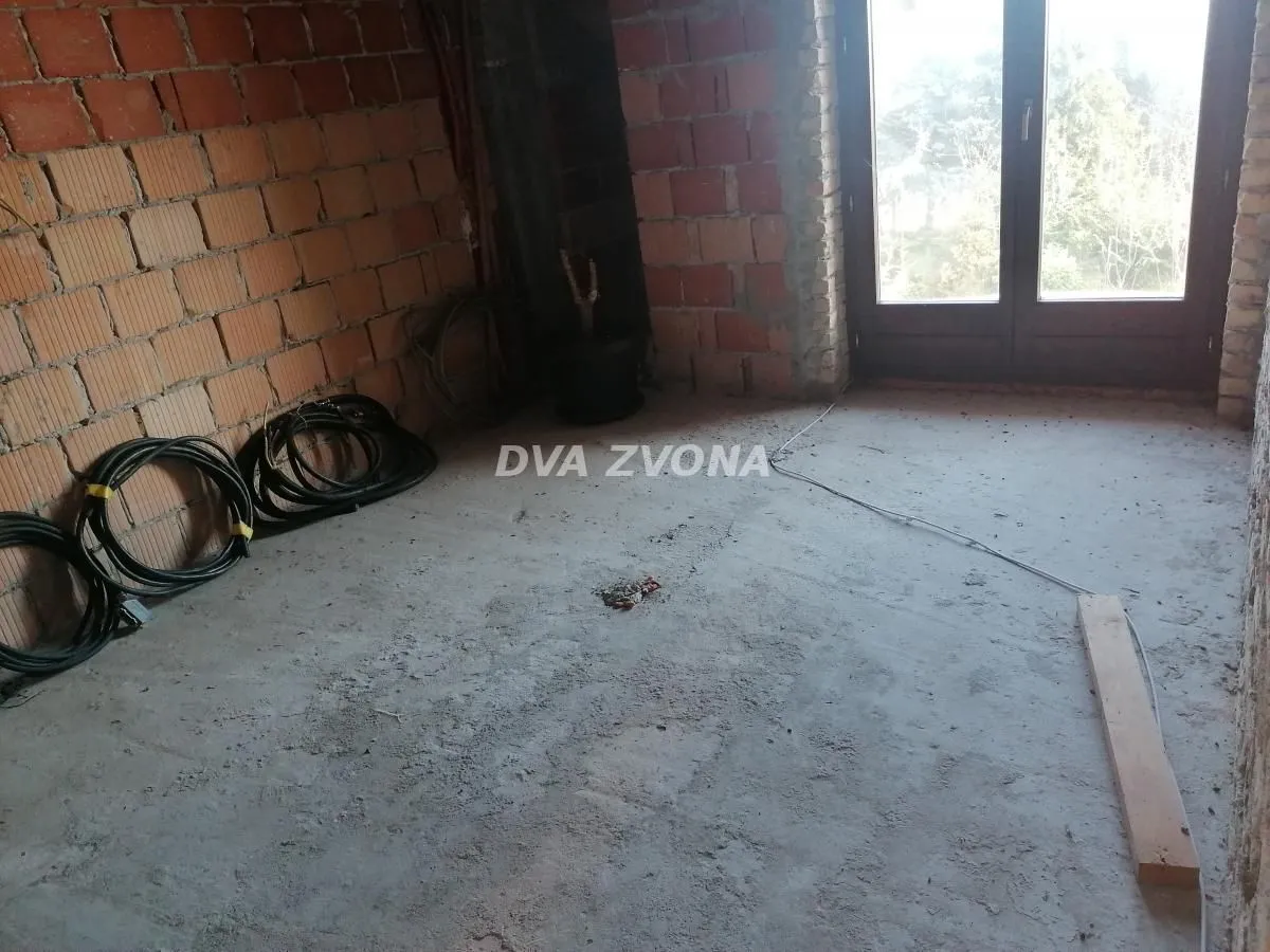 Unfinished room in raw construction phase with brick walls and balcony doors.