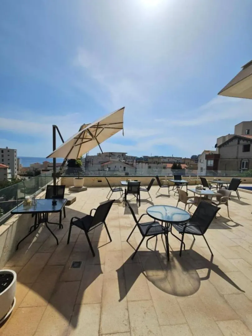 Spacious rooftop terrace with tables, chairs, and umbrellas.