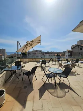 Spacious rooftop terrace with tables, chairs, and umbrellas. - image 21