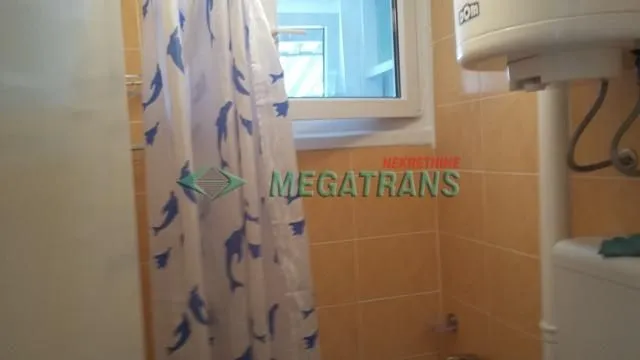 Manje kupatilo sa pločicama, tuš kabinom i bojlerom.