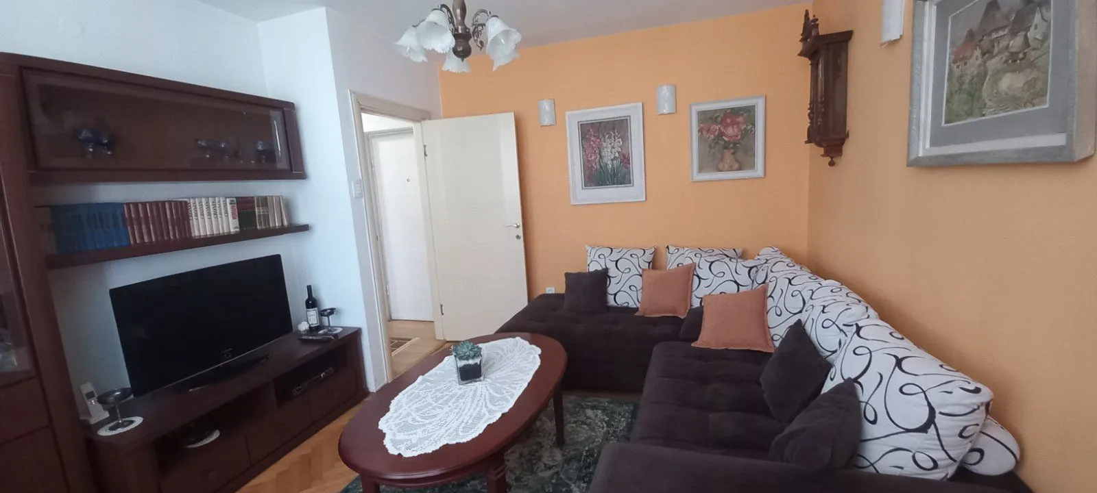 A living room featuring a corner sofa, a coffee table, and a television unit.