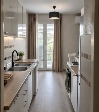 Dugačka bijela kuhinja sa sudoperom, ugradnim uređajima i izlazom na terasu. - image 3