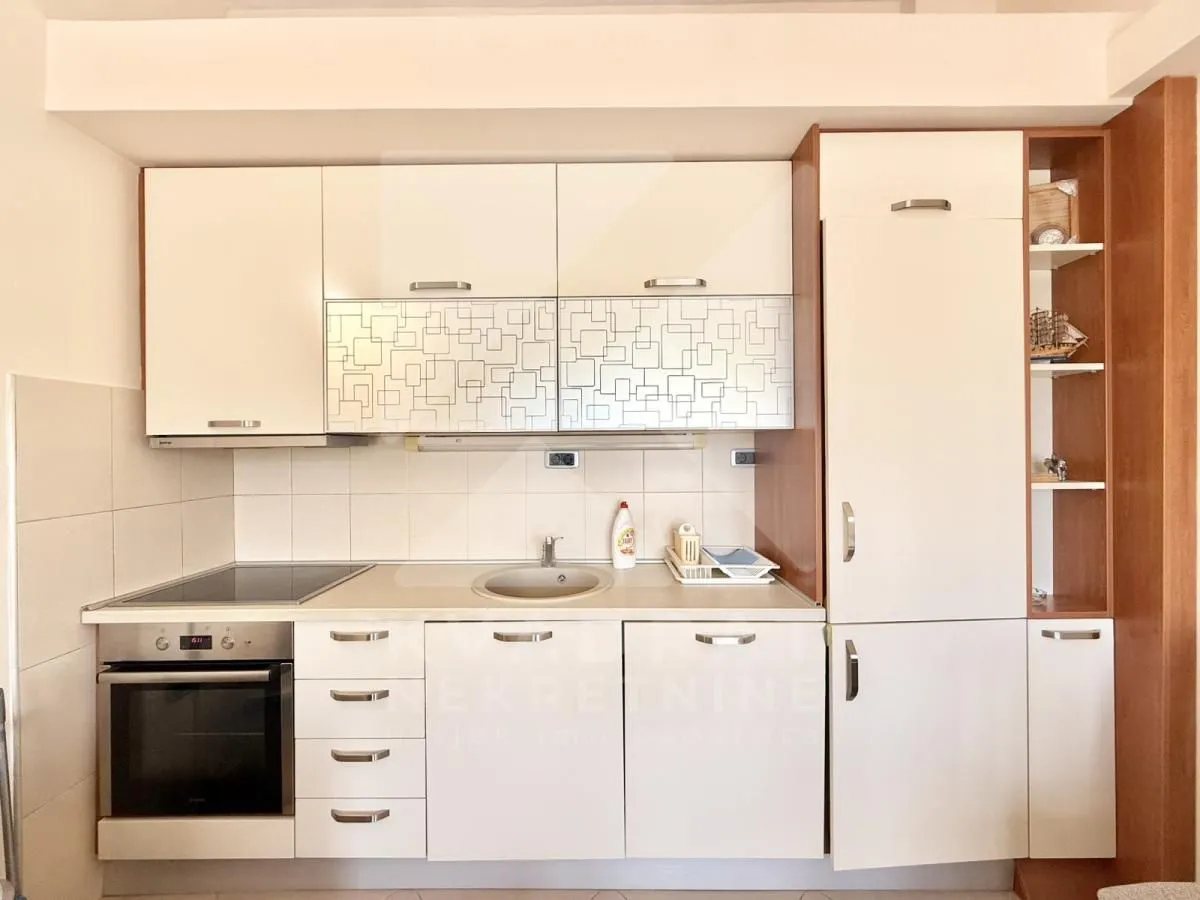 Small kitchen with white cabinets, built-in oven and hob.