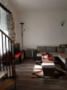 Living room with a sofa, TV, and staircase. - image 11