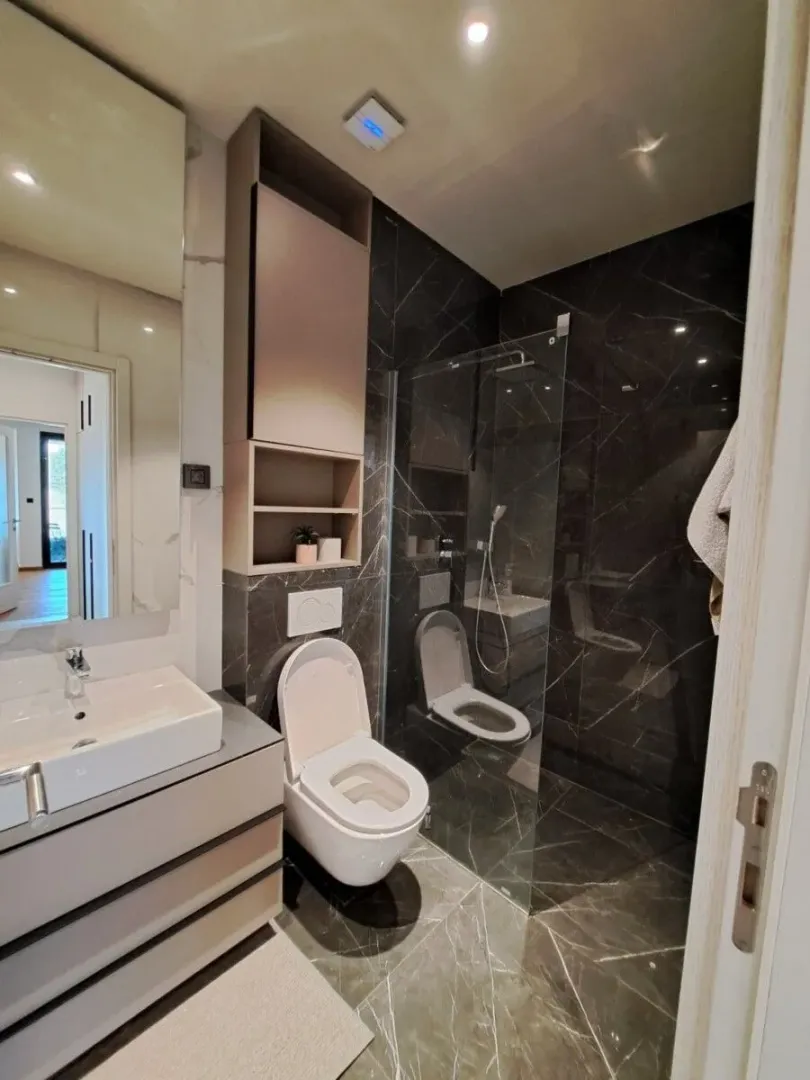 Moderne kupatilo sa tuš kabinom, umivaonikom i ugradnom wc šoljom.