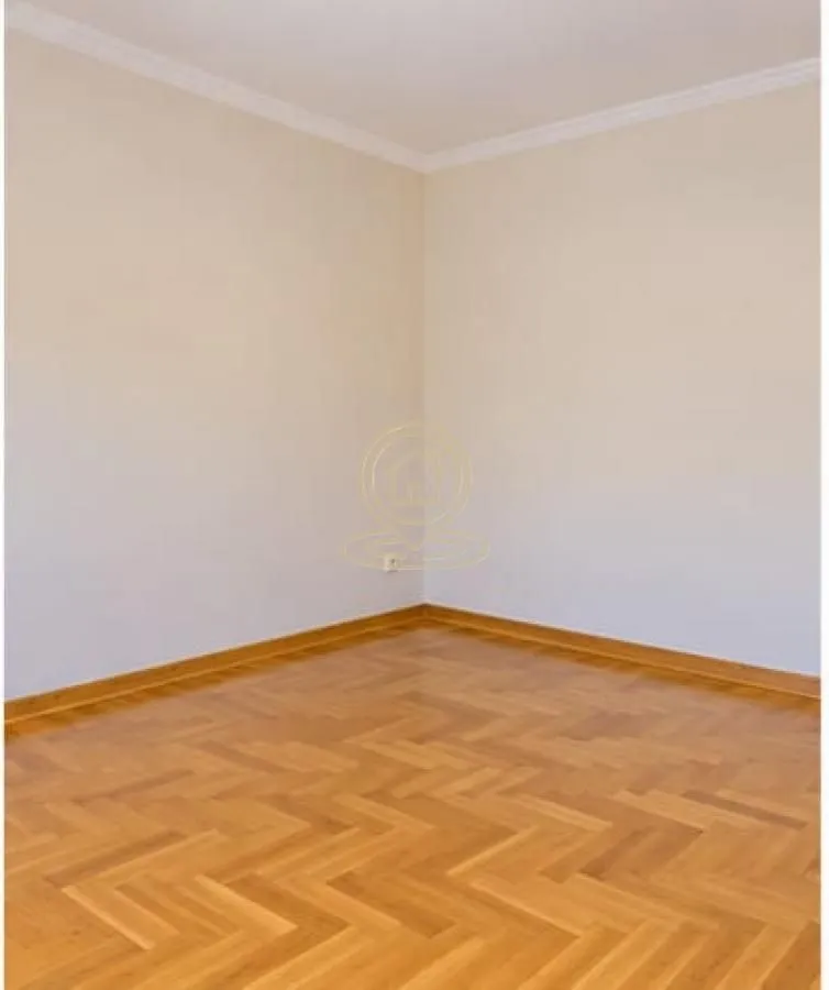 Empty room with parquet flooring and light walls.
