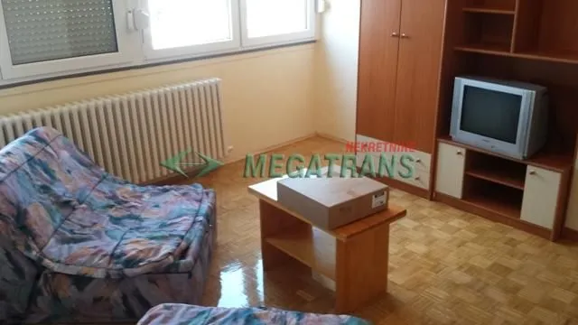 Dnevna soba sa garniturom, drvenim stočićem i TV komodom.