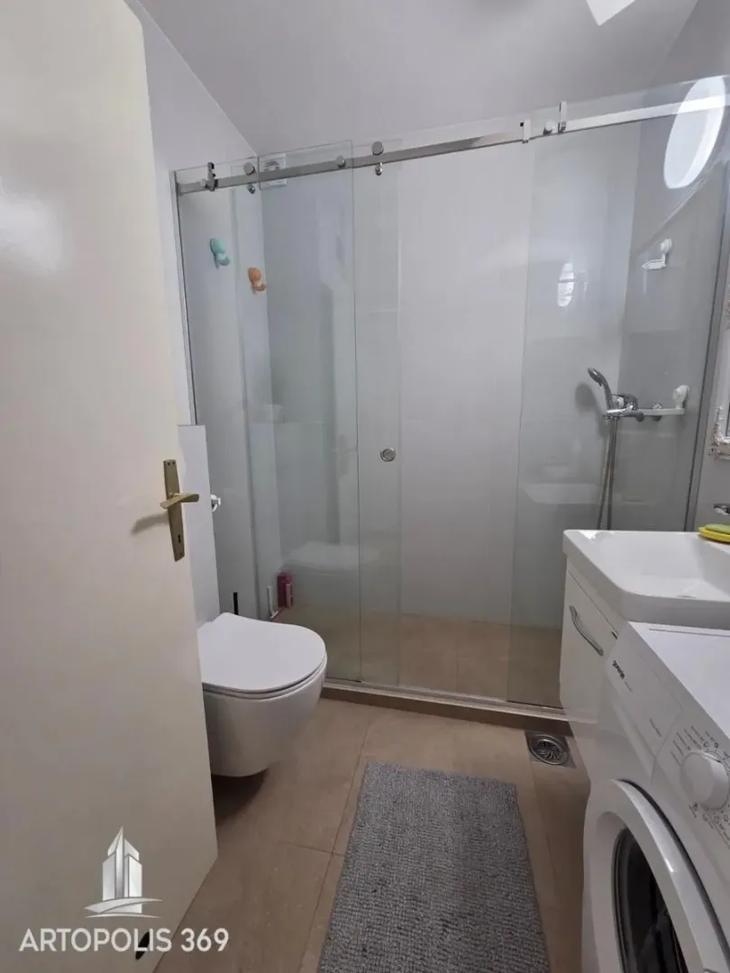 Kupatilo sa tuš kabinom, WC šoljom i umivaonikom sa mašinom za veš.