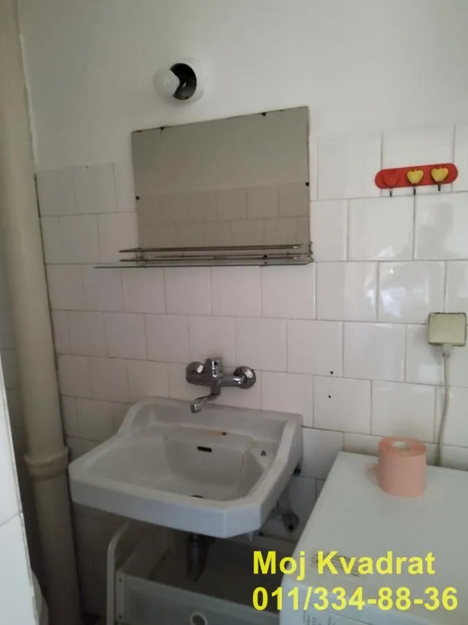 Small bathroom with a washbasin, mirror, and white wall tiles.