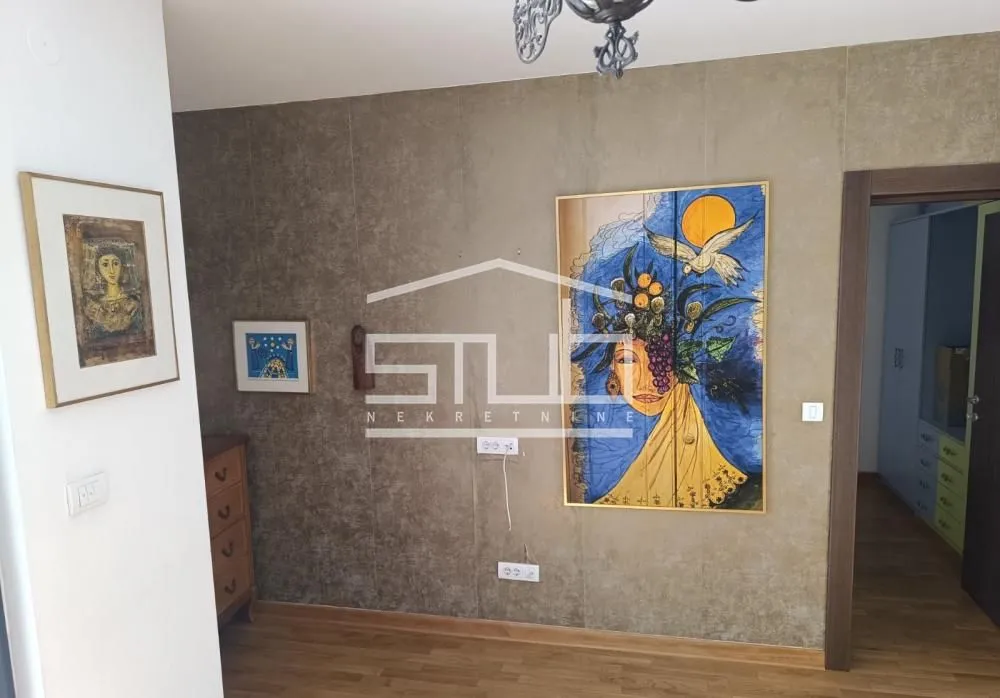 Dnevni boravak sa slikama na zidu i pogledom na prolaz prema sobi.