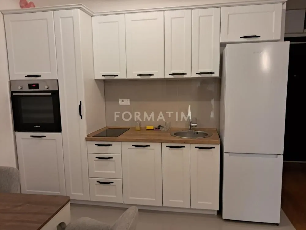 Small white kitchen with built-in appliances and a refrigerator.
