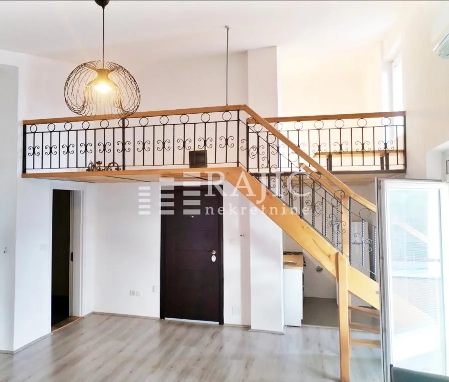 Living room with a gallery and wooden stairs.