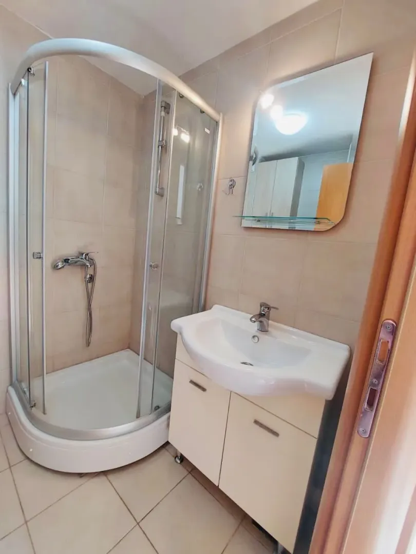 Small bathroom with a shower cabin, washbasin, and mirror.