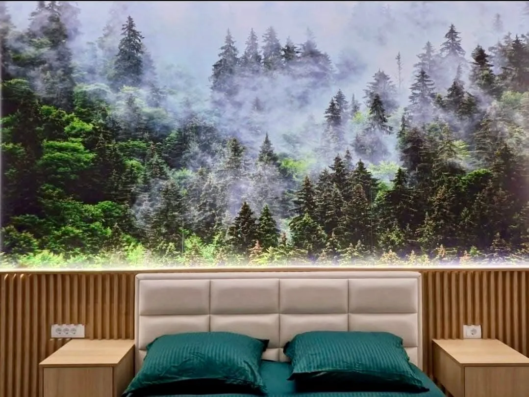 Modern bedroom with forest wallpaper and wooden wall paneling.