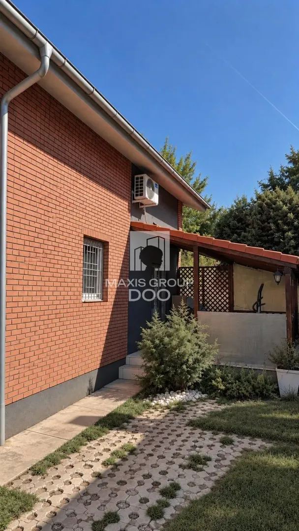 Pogled na spoljašnji deo kuće sa popločanim dvorištem i nadstrešnicom.