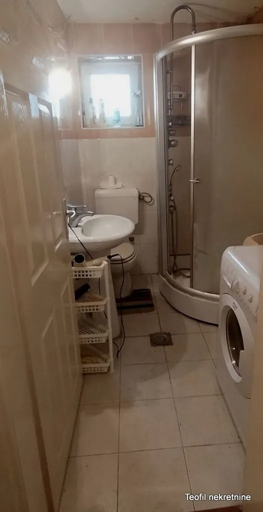 Manje kupatilo sa tuš kabinom, umivaonikom i veš mašinom.