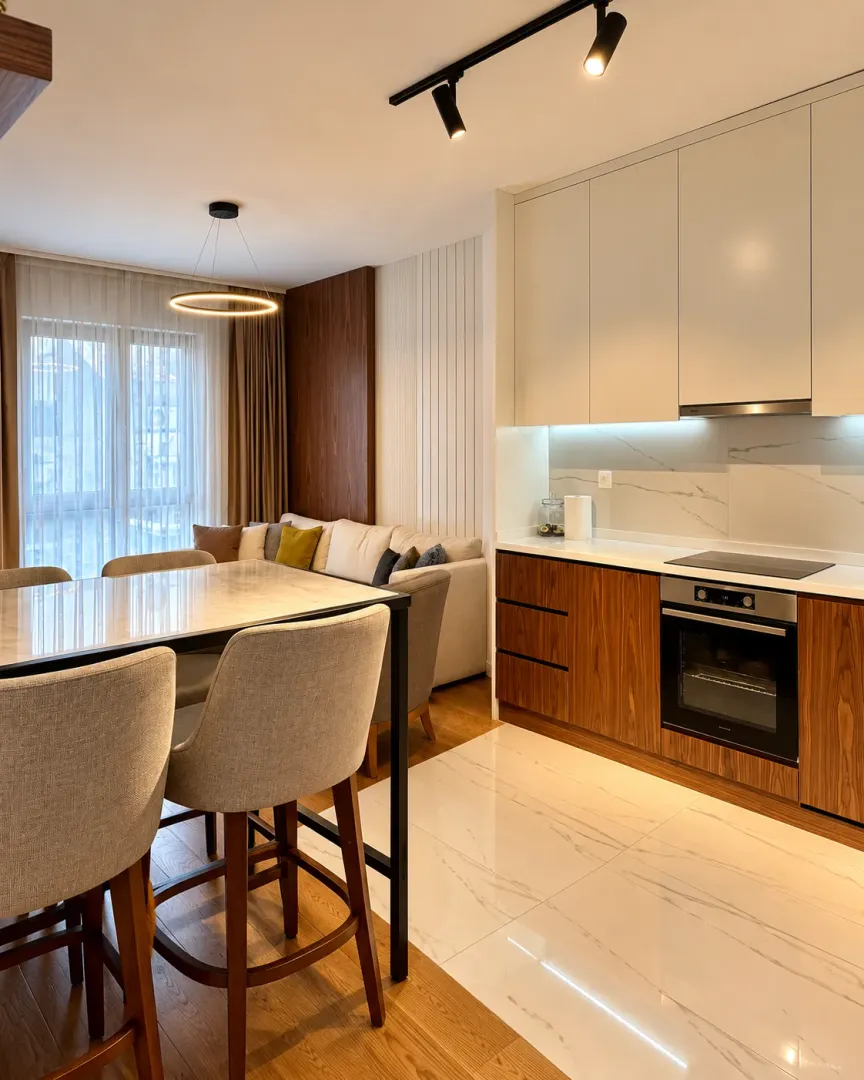 Modern kitchen with dining area and living room in light tones.