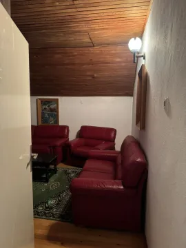 Dnevna soba u potkrovlju sa crvenom kožnom garniturom i drvenim plafonom. - image 9