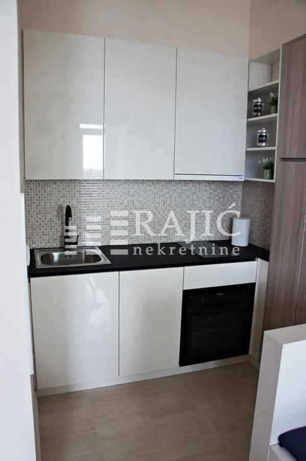 Small equipped kitchen with white cabinets and a built-in oven.