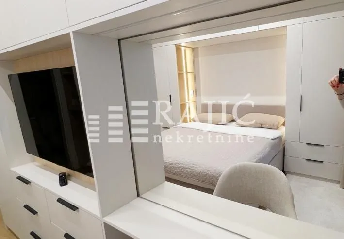 View from the living area towards the bedroom with a bed and fitted wardrobes.