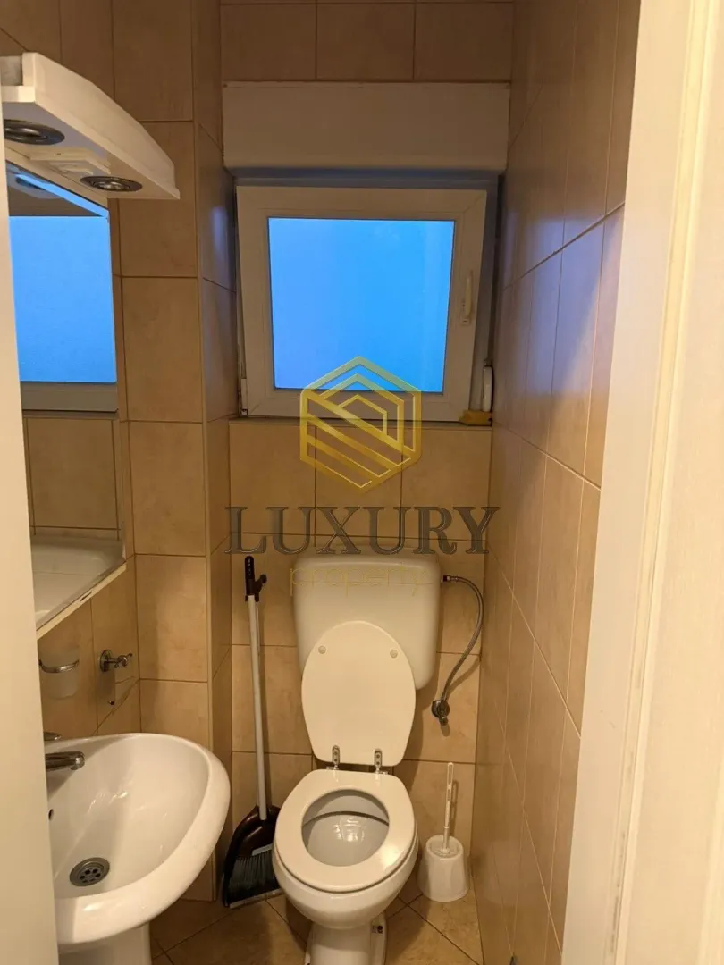 Smaller bathroom with a toilet, washbasin, and beige tiles.