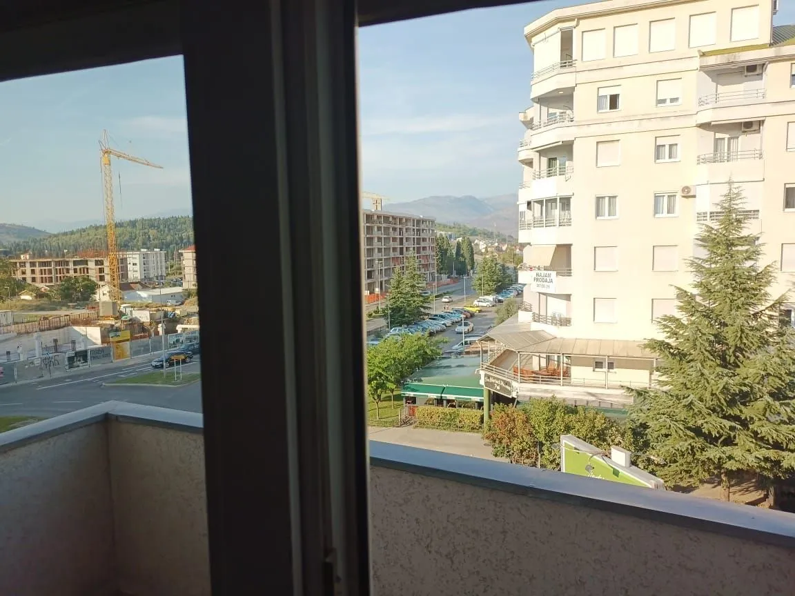 Pogled sa balkona na okolne zgrade i gradski pejzaž.